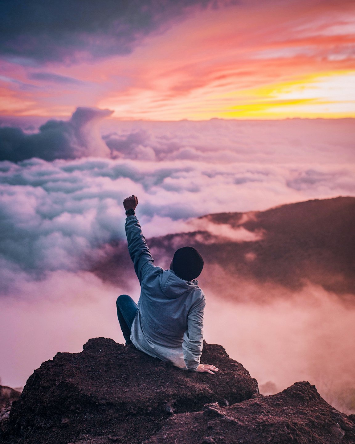 Person sitting on mountain cliff
